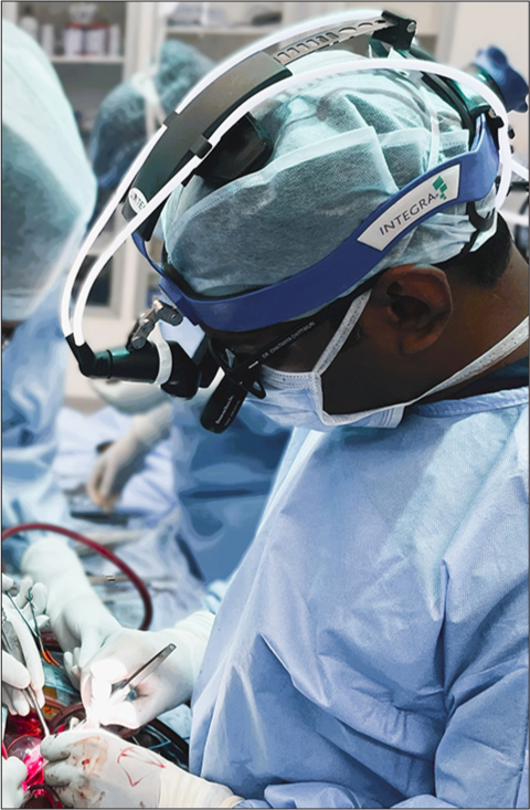 Cardiac surgeon in surgical attire, wearing vascular loupes and headlight.